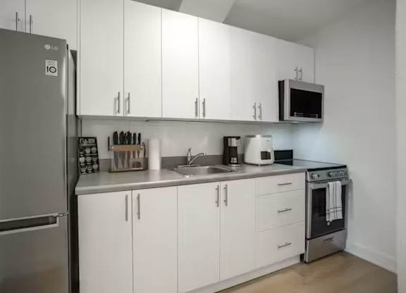 A kitchen with white cabinets and a stainless steel refrigerator.