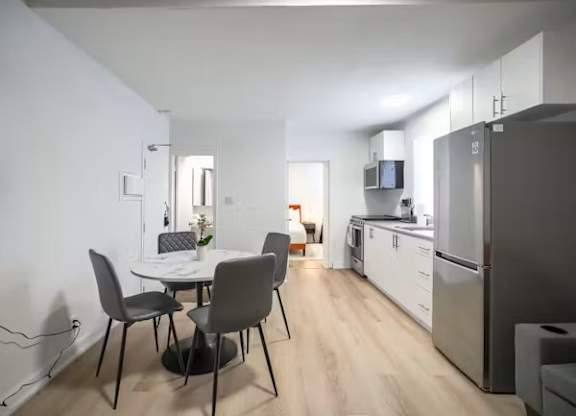 A kitchen with a table and chairs in the foreground and a refrigerator in the background.