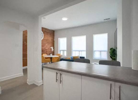 A kitchen with white cabinets and a brick wall.