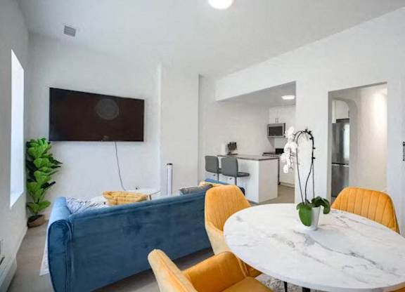 A living room with a blue couch, yellow chairs, and a white table.