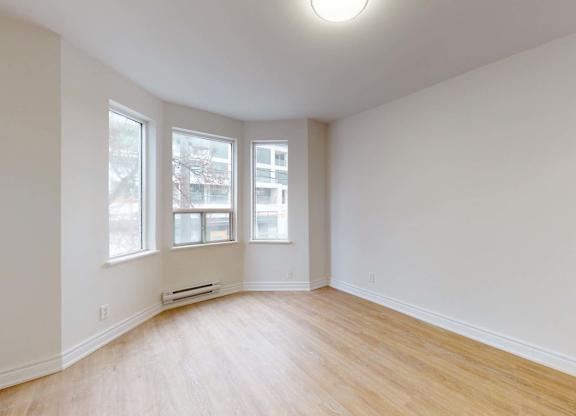 A room with a window and a wooden floor.