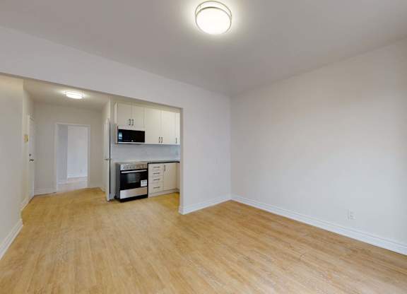 A spacious room with a kitchenette and wooden flooring.