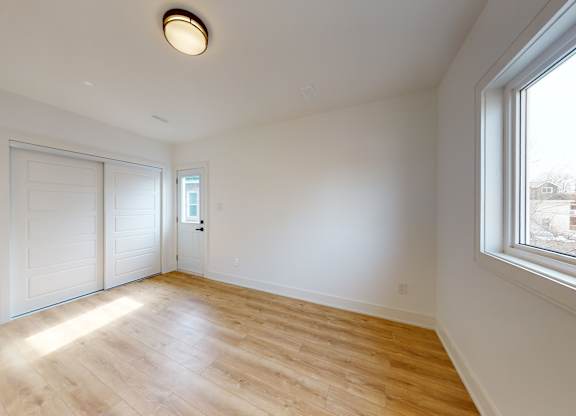A room with a window and a wooden floor.