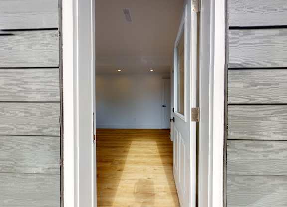 A hallway with wooden floors and white walls.