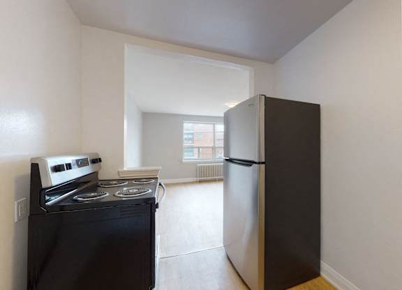 A black fridge and stove in a small kitchen.