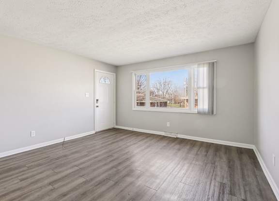 A room with a wooden floor and a window showing a snowy landscape outside.