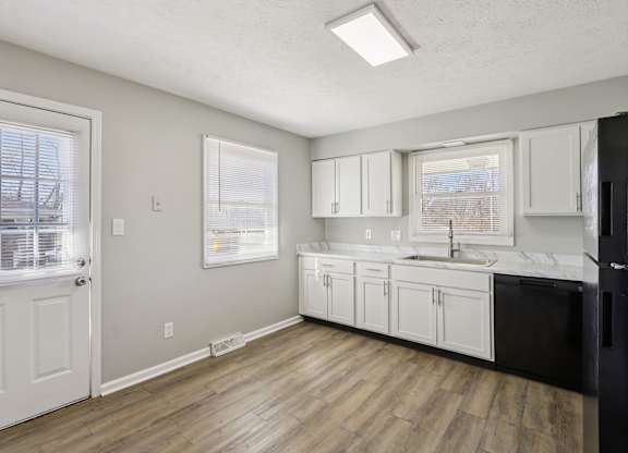 A kitchen with white cabinets and a black fridge.