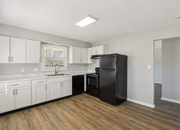 A kitchen with black appliances and white cabinets.