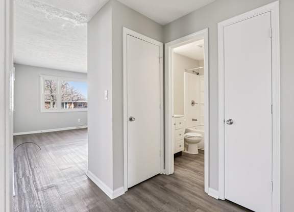 A bathroom with a toilet, sink, and mirror is visible through an open door.
