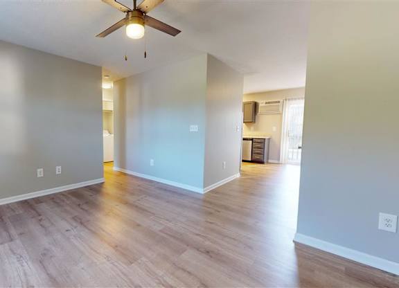 A room with a ceiling fan and light fixture, hardwood floors, and a doorway leading to another room at Ridgeview Apartments, Fortville, Indiana