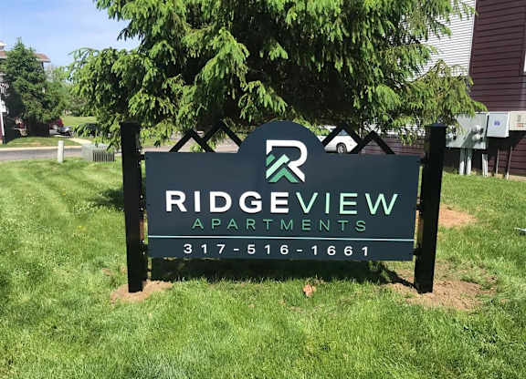 A sign for Ridgeview Apartments is displayed in front of a tree at Ridgeview Apartments, Fortville, Indiana