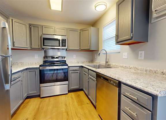A kitchen with a stainless steel refrigerator and wooden floors at Ridgeview Apartments, Fortville, Indiana