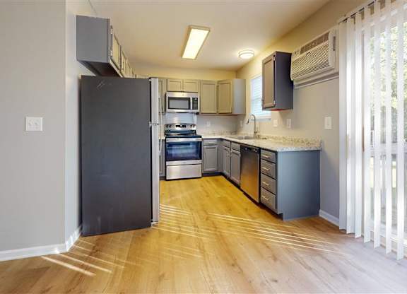 A kitchen with a black refrigerator and wooden floors at Ridgeview Apartments, Fortville, IN
