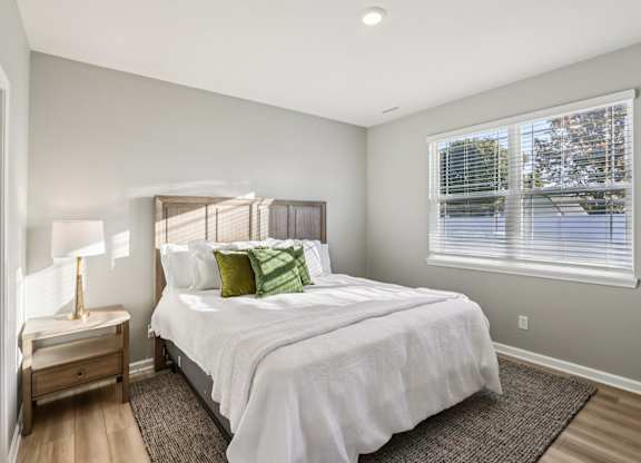 A bedroom with a large bed and a window with blinds.