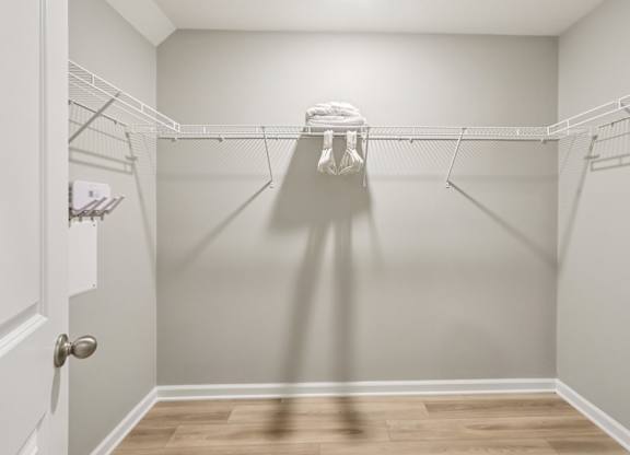 A white closet with a white door and a white shelf on the left.