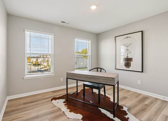 A room with a table and a cowhide rug in front of a window.