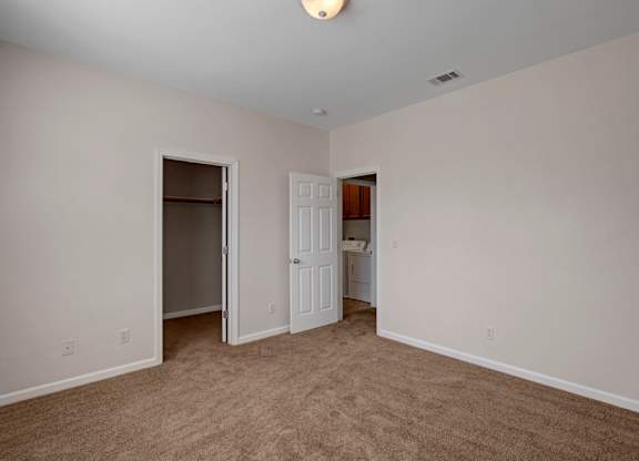 A room with a carpeted floor and a white door.