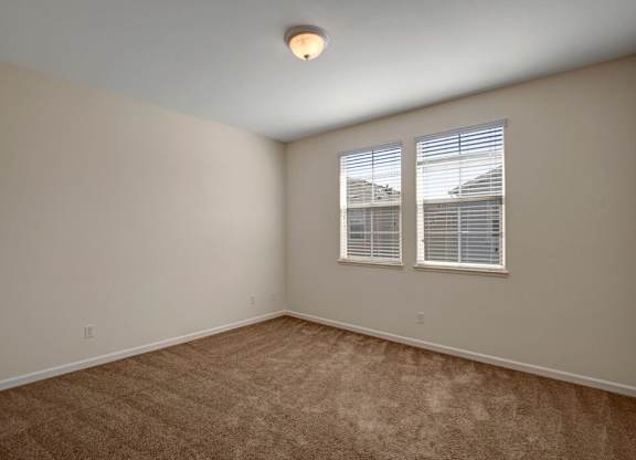 A room with carpeted floor and a window with blinds.