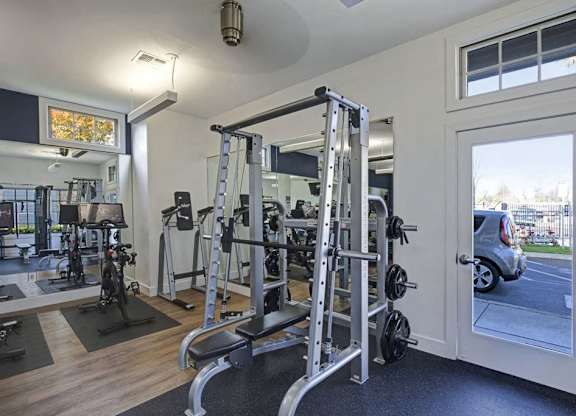 A home gym with a variety of equipment including a squat rack, bench, and weights.