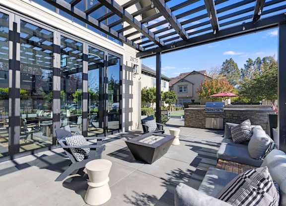A modern outdoor patio with a glass wall and a stone fireplace.