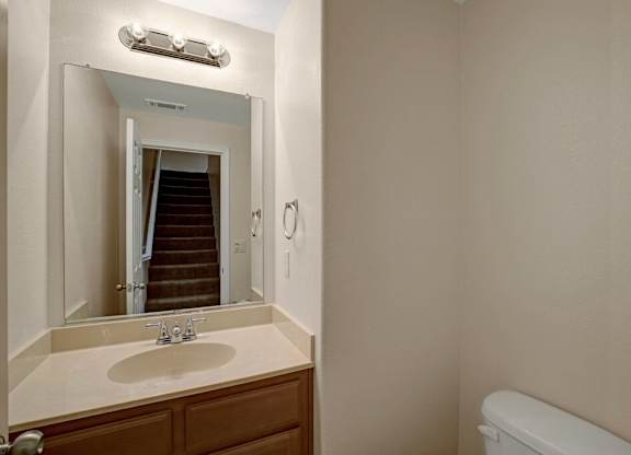 A bathroom with a sink, mirror, and toilet.
