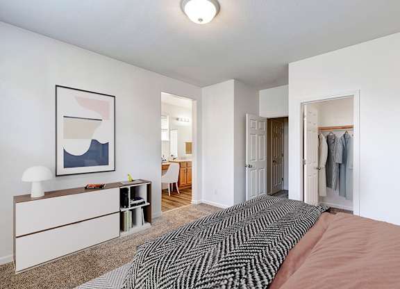 A bedroom with a bed, a desk, and a chair.