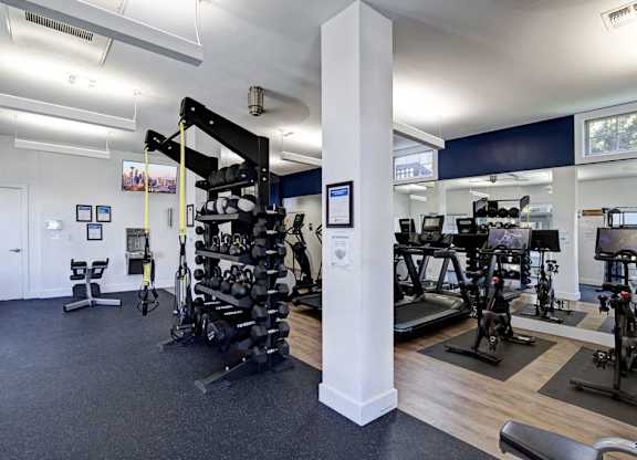 A gym with a variety of equipment including treadmills, weights, and exercise bikes.