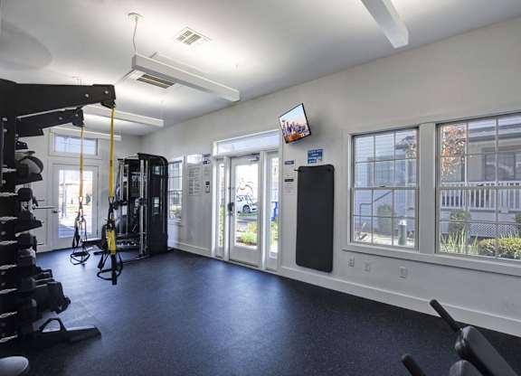 A gym with a variety of equipment including a treadmill, weights, and a television.