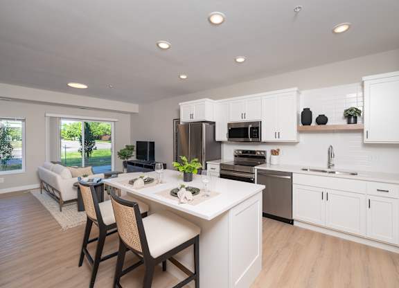 A modern kitchen with white cabinets and a dining table.