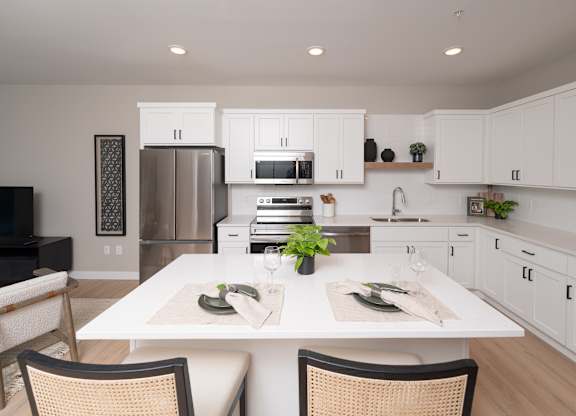 A modern kitchen with a dining table set for two.