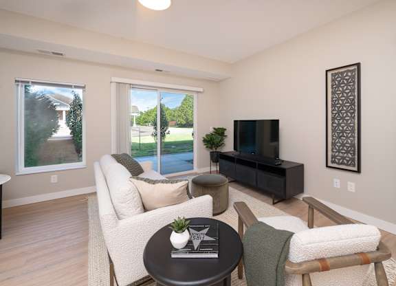 A living room with a white couch, a black coffee table, and a flat screen TV.