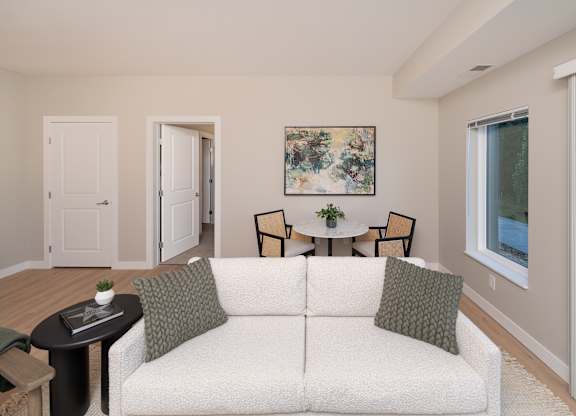 A living room with a white couch and a painting on the wall.