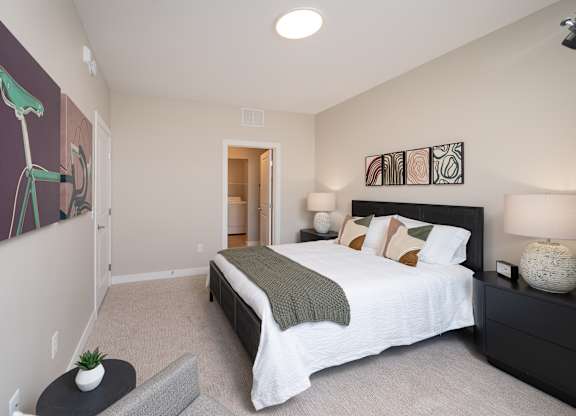 A bedroom with a large bed and a painting of a bicycle on the wall.