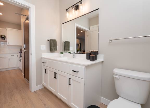 A white bathroom with a toilet, sink, and mirror.