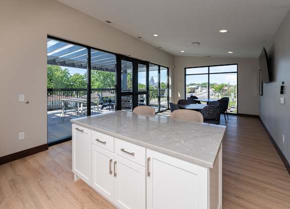 An upstairs community kitchen with white cabinets and a marble countertop.