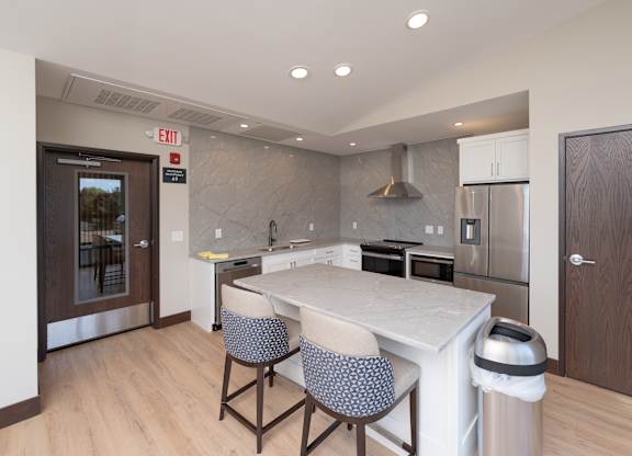 A kitchen with a white counter top and two chairs.