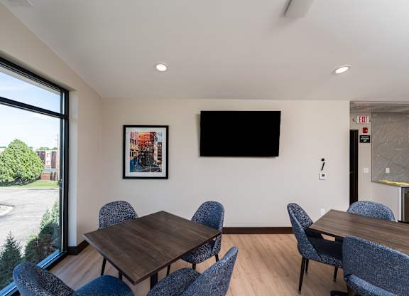 A conference room with a table, chairs, and a TV mounted on the wall.