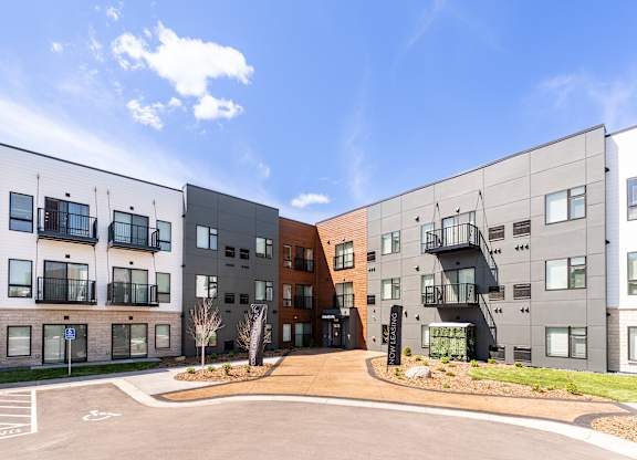A modern apartment complex with a parking lot in front.