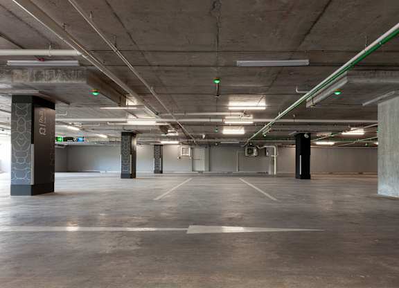 A large, empty parking garage with concrete pillars and a concrete floor.