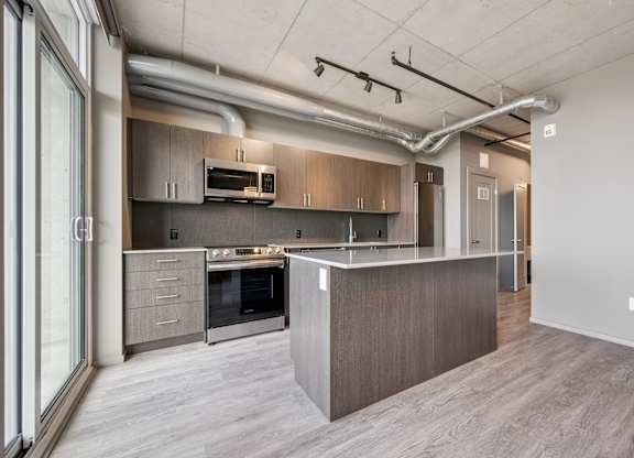 Modern kitchen with island and stainless appliances at Ophelia on Queen Apartments, Ontario