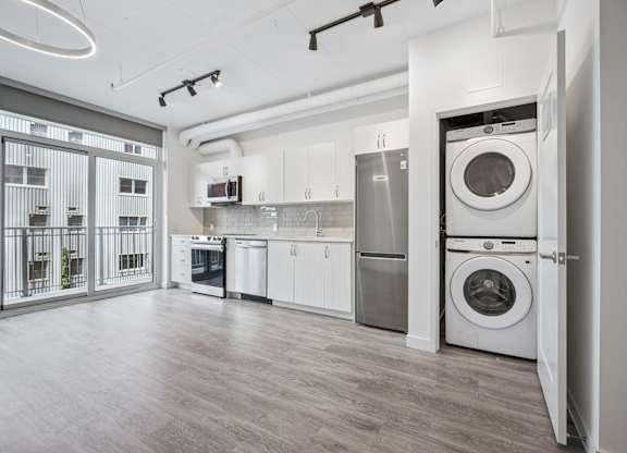 Open concept kitchen with stackable washer dryer at Ophelia on Queen Apartments, Kitchener, Ontario