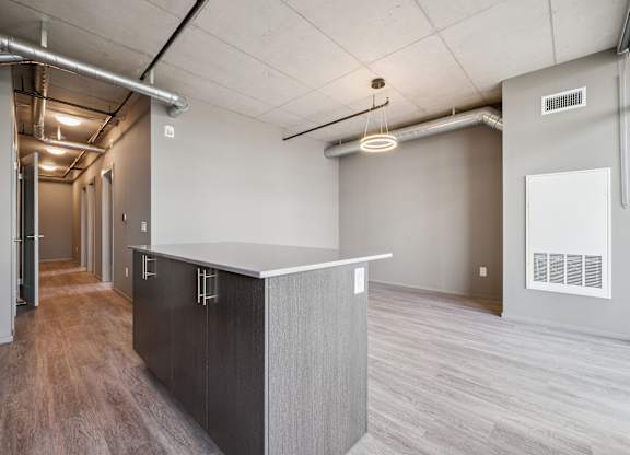 Contemporary kitchen island with exposed ceiling ducts at Ophelia on Queen Apartments, Kitchener, ON N2G 0E7
