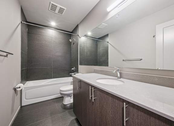 Bathroom with dark tile and white countertop at Ophelia on Queen Apartments, Kitchener, ON