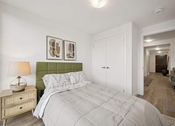 Bedroom with green headboard and neutral bedding at The Maverick Apartments, Kitchener, ON N2H 0E3