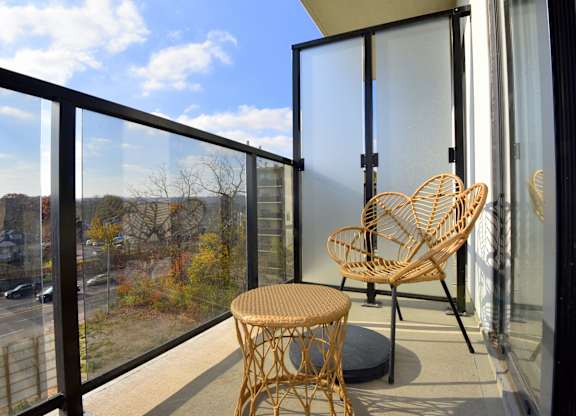 A balcony with a chair and table at Roxy Apartments, Hamilton, ON, L8H 0B7