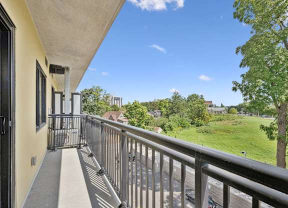 Balcony view overlooking green space and trees at The Maverick Apartments, Kitchener, ON