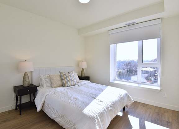 A bedroom with a large bed and two lamps on side tables at Roxy Apartments, Ontario