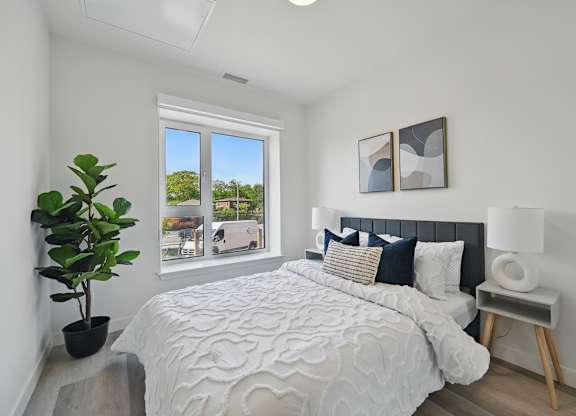 A bedroom with a large bed and a potted plant at Roxy Apartments, Hamilton, ON