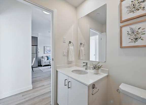 A white bathroom with a sink, mirror, and a bathtub at Roxy Apartments, Ontario