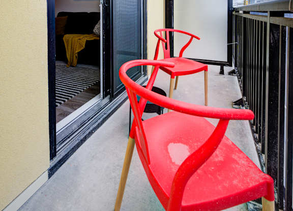 A red chair sits on a balcony at The Maverick Apartments, Ontario, N2H 0E3